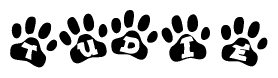 The image shows a series of animal paw prints arranged horizontally. Within each paw print, there's a letter; together they spell Tudie