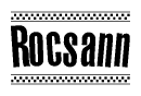The image is a black and white clipart of the text Rocsann in a bold, italicized font. The text is bordered by a dotted line on the top and bottom, and there are checkered flags positioned at both ends of the text, usually associated with racing or finishing lines.