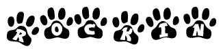 The image shows a series of animal paw prints arranged in a horizontal line. Each paw print contains a letter, and together they spell out the word Rockin.