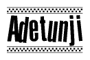 The image is a black and white clipart of the text Adetunji in a bold, italicized font. The text is bordered by a dotted line on the top and bottom, and there are checkered flags positioned at both ends of the text, usually associated with racing or finishing lines.