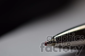 The photo shows the tip of a pen, close up, with a gray blurred background